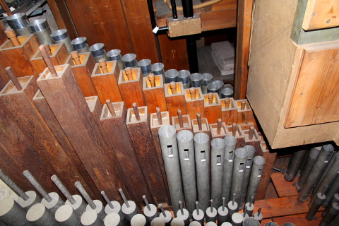 La tuyauterie du grand-orgue "passant" sous une des boîtes. Photo du 02/11/2014.Noter les deux types de facture des tuyaux en bois. Ceux du haut sont du 20ème.On distingue aussi les parties sommitales du Clairon 4', de 2001 et plus brillantes :le jeu a dû être restauré car il avait été découpé à la pince en 1978.