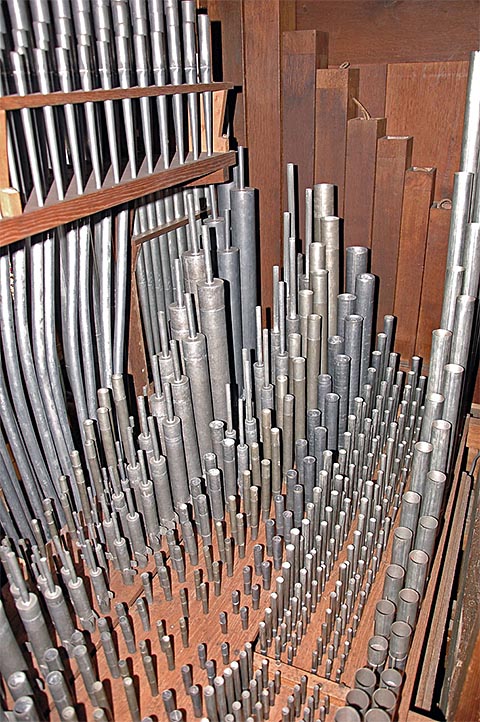 De gauche (façade) à droite (accès) : les
                    longs postages courbés du Cornet,(le Cornet lui-même est visible en partie
                    en haut à gauche), le Prestant, la Flûte 4', le Bourdon(ses basses en bois
                    sont au fond contre les côtés), le Nasard, la Doublette, la Tierce, la
                    Fourniture, la Cymbale et le Cromorne. Noter la couleur de la Doublette et
                    du Prestant (étain de 1746).
