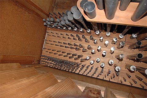 Une partie (le sommier avant côté C) de la
                    tuyauterie du récit.Tout en bas (près des jalousies ouvertes, donc vers
                    l'avant de l'instrument), la Cymbale.En haut de l'image, les tuyaux évasés
                    du Basson/Hautbois.