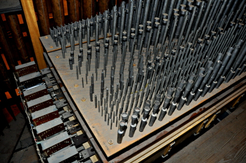 Une vue sur la tuyauterie du grand-orgue.
Il s'agit du côté droit de la partie en encorbellement de l'instrument.
En haut à gauche, le revers de la façade (tuyaux en cuivre).
Ce sont les tuyaux aigus de tous les jeux du grand-orgue :
le sommier étant chromatique, ils sont tous dans l'ordre.
Le nom des jeux est gravé au bout des faux-sommiers.
En partant d'en bas à droite (passerelle séparant le grand-orgue du récit)
vers la façade : le Cromorne, la Cymbale, la Fourniture, la Flûte 4',
la Doublette, le Prestant, le Bourdon 8', la Montre, puis le Cornet.
Ce Cornet n'est donc pas posté en hauteur, comme à l'époque classique,
mais on lui a tout de même attribué la chape avant, juste derrière la façade.