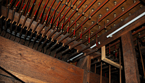 Vue de dessous du sommier de grand-orgue.La vergette (reliée à la touche du clavier par des équerres) fait basculerun balancier qui soulève une réglette (horizontale rouge) poussant un piston pour chaque tuyau.