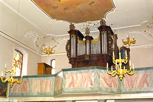 Une vue de l'orgue avant sa restauration
                    (25/06/2000).Les ornements étaient encore dorés.On distingue le
                    positif provisoire qui avait été installé à la tribune.Les éléments de
                    soufflerie n'étaient pas logés en haut à gauche du buffet.La façade était
                    postiche, avec une hauteur et une ligne des bouches complètement
                    fantaisiste.
