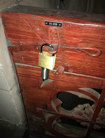 La commande du Bretzelmann,
au revers du garde-corps faisant face au chœur.
Photo de Frédéric Moser, 2023.
Noter le calibre du cadenas, annonçant clairement "N'y pense même pas".
Il faut dire que sans lui, même quelqu'un de très très très sérieux n'aurait
qu'une chance infinitésimale de ne pas manipuler le levier, juste un peu,
au moins la 1ère fois...